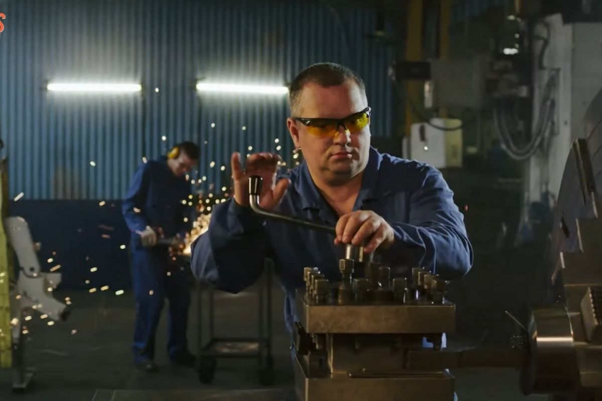 Radnik u industrijskom okruženju obavlja metaloprerađivačke poslove u hladnom prostoru sa zaštitnim naočarima i radnom odećom