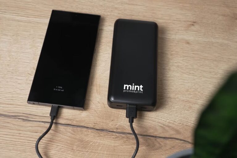 Pametni telefon povezan na punjač i power bank na radnom stolu u kancelariji